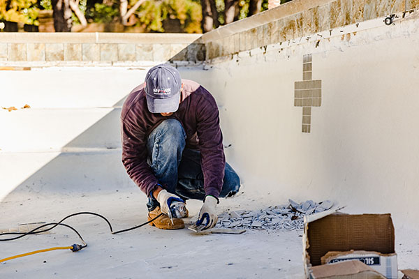 man renovating pool after unexpected expenses during pool renovations